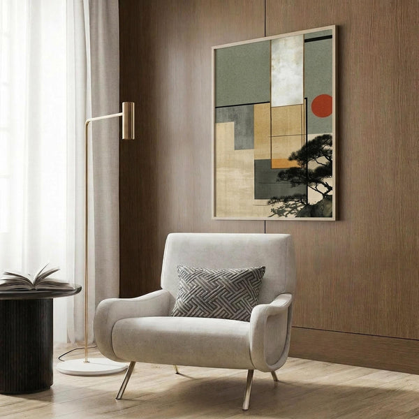 May include: Framed abstract artwork with geometric squares in sage green, warm beige, orange, and gray tones, featuring a black silhouette of a pine tree and red circle accent. Displayed above a cream upholstered armchair with geometric patterned pillow in a modern living room with wood paneled walls, brass floor lamp, and side table.