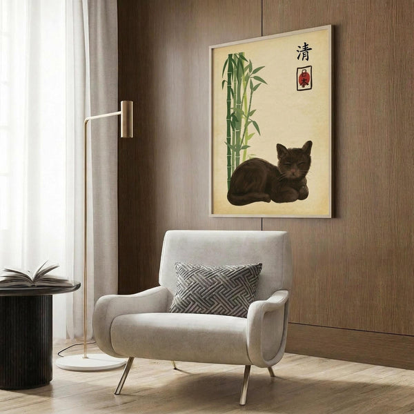 May include: Framed Japanese-style artwork featuring a dark gray tabby cat resting beside green bamboo stalks on cream background with red seal stamp and black characters, displayed on wood paneled wall above beige upholstered armchair with geometric patterned pillow, brass floor lamp and side table visible in modern living room setting