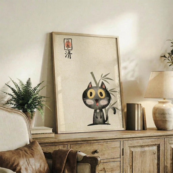 May include: Framed poster featuring a cute black cat with large yellow eyes and pink tongue sitting among bamboo stalks, with Japanese characters at top. Light wood frame displayed on rustic wooden sideboard alongside fern plant, books, ceramic vase, and brown leather furniture in warm, neutral-toned living room setting.