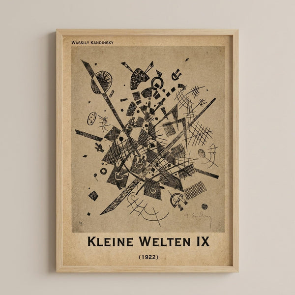 May include: Framed art print displaying Wassily Kandinsky's abstract composition with dynamic black geometric shapes, lines, and scattered elements on beige textured paper background. The wooden frame hangs on a light gray wall, showing intricate details of intersecting forms, crosshatched patterns, circles, and angular fragments arranged in an energetic central burst.
