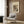 May include: Framed Wassily Kandinsky abstract art print with colorful geometric shapes in circular composition on cream background, displayed on wood paneled wall above modern beige armchair with geometric pillow, beside brass floor lamp and dark side table with open book