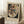 May include: Abstract Kandinsky poster in light wood frame leaning against white wall in cozy room setting. The artwork features colorful geometric shapes, lines, and forms in red, blue, yellow, and black arranged in an oval composition. Small wooden side table with white coffee cup and saucer sits nearby on textured cream rug. Soft natural lighting creates gentle shadows on the wall.