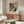 May include: Kandinsky abstract art poster displayed above wooden sideboard in modern living room. Colorful geometric shapes and lines within oval form on cream background. White curved chair, glass coffee table, and brass floor lamp visible. Poster shows vibrant reds, blues, yellows against black background with museum attribution text below artwork.