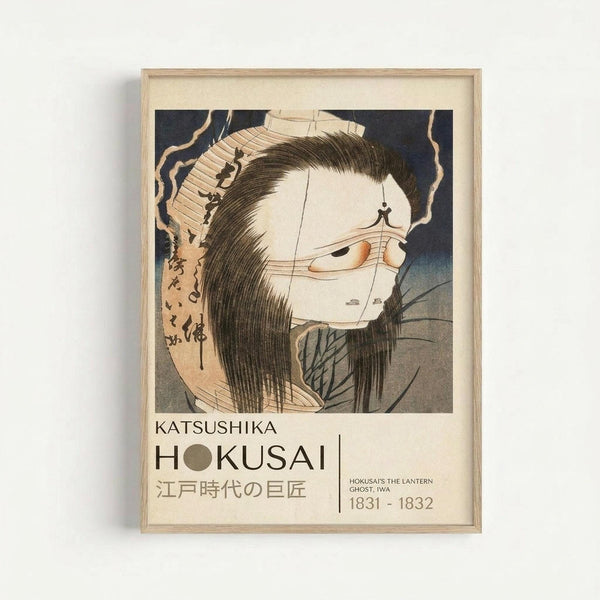 May include: Framed Japanese woodblock print featuring a ghostly female figure with long black hair and pale white face against dark background. The artwork shows traditional ukiyo-e style with Japanese text. Displayed in light wooden frame with cream matting on white wall. Print includes title "KATSUSHIKA HOKUSAI" and dates "1831-1832" below the image.