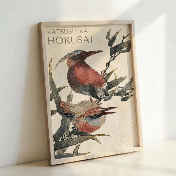 May include: Framed art print featuring two colorful birds perched on bamboo branches in traditional Japanese woodblock print style. The birds display reddish-brown and blue plumage with long curved beaks. Set in a light wooden frame against a white wall, the vintage-style artwork shows detailed brushwork with muted earth tones and elegant calligraphy at the top.