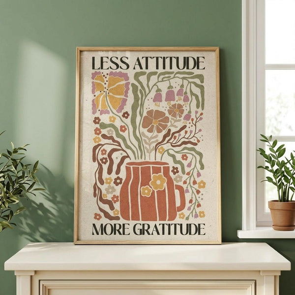 May include: Framed poster with whimsical illustration featuring a red coffee mug with colorful floral steam design including butterflies, flowers, and decorative swirls in earthy tones of orange, green, pink and brown on cream background. Natural wood frame displayed on white wooden surface against sage green wall with houseplants and window visible.