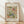 May include: Framed botanical print featuring William Morris's ornate floral pattern in muted greens, coral pink, and blue tones against cream background. The decorative design shows flowing leaves, stylized flowers, and curving vines in Arts and Crafts style. Natural wood frame sits on light wooden floor against white wall with soft shadows from natural lighting.