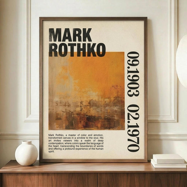May include: Framed poster displaying abstract orange and brown textured artwork with "MARK ROTHKO" in bold black letters and "1903 1970" along the right side. Includes descriptive text about the artist below the image. Shown leaning against white paneled wall on wooden surface next to white ceramic vase and stack of books in bright interior setting.