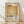 May include: A framed poster with Mark Rothko's name in bold black letters at the top, featuring a large golden-yellow abstract color block in the center, with "Rothko" and "02.1970" text below, plus a small paragraph of descriptive text. The cream and tan colored print is displayed in a light wood frame, leaning against a white textured wall on wooden flooring with natural sunlight casting diagonal shadows across the scene.