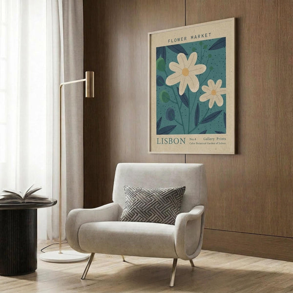 May include: Vintage-style botanical poster featuring white daisies on teal background with "Flower Market" and "Lisbon" text, displayed in light wood frame above beige upholstered armchair with geometric patterned pillow. Modern brass floor lamp and black side table with open book complete the neutral-toned living room setting with wood paneled walls.