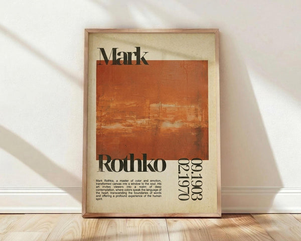 May include: Framed poster print with cream background featuring large orange-red abstract rectangular color block. Black text reads "Mark Rothko" with years "02.1970" vertically along right side. Small descriptive paragraph appears at bottom left. Wooden frame sits on light wood floor against white wall with soft natural lighting creating diagonal shadows.