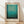 May include: Framed poster print of abstract color field artwork featuring gradient turquoise and teal tones transitioning to darker green-black at bottom, displayed in light wood frame against cream textured wall with natural lighting creating diagonal shadows across wooden floor.