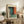 May include: Framed abstract art print with teal, orange, and dark color blocks in Rothko style, displayed on rustic wooden sideboard alongside fern plant, ceramic vase, and books in neutral-toned living room setting with beige chair and cream walls