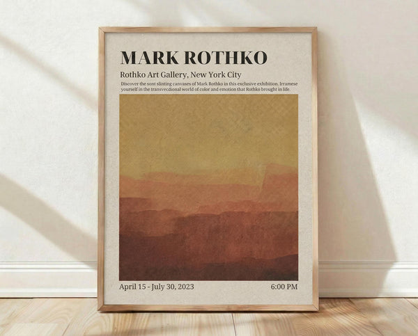 May include: Framed exhibition poster with Mark Rothko's name in bold black letters at top, featuring abstract color field artwork transitioning from golden yellow at top to deep reddish-brown at bottom. White matting surrounds the design with exhibition details and dates below. Light wood frame displayed on wooden floor against cream wall with soft window lighting creating diagonal shadows.