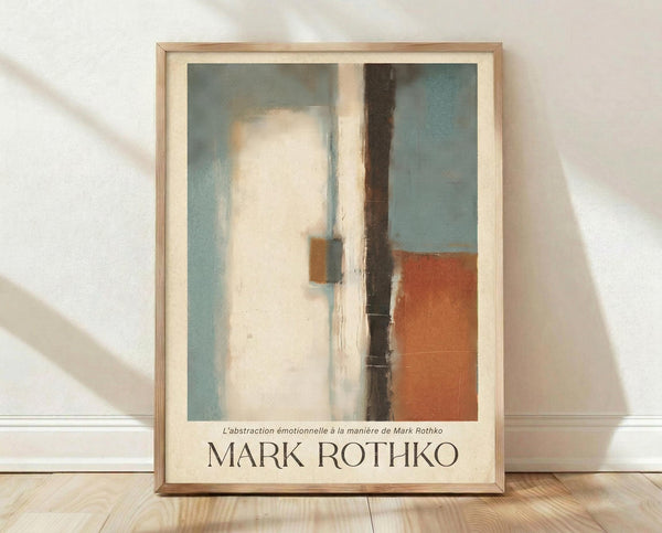 May include: Framed abstract art print in light wood frame leaning against white textured wall on light wooden floor. Artwork features vertical composition with muted blue-green, cream white, dark brown, and rust orange color blocks in soft, blended style. French text below image reads "L'abstraction émotionnelle à la manière de Mark Rothko" above "MARK ROTHKO" in brown lettering. Natural lighting creates gentle shadows on wall.