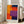 May include: Framed abstract art print with bold geometric color blocks in orange, red, purple, and blue arranged in rectangular sections. The poster features "MARK ROTHKO" text at bottom in black letters. Shown leaning against white wall next to beige upholstered chair in bright living room with large windows and hardwood floors.