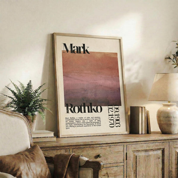 May include: Framed art print with Mark Rothko's name and warm gradient colors from peach to deep burgundy, displayed on rustic wooden sideboard alongside fern plant, ceramic vase, stacked books, and brown leather furniture in neutral-toned living room setting.