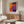 a modern living room with a large abstract painting on the wall, a wooden cabinet, a white sofa, and a glass coffee table.