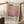 May include: Person holding large framed poster featuring abstract orange and purple gradient artwork with "Mark Rothko" text and biographical description. Light wooden frame, white matting, displayed in bright room with coffee cup on wooden surface and soft textiles nearby.