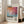 May include: Framed poster with abstract colorful artwork in vibrant pink, orange, blue and white brushstrokes, featuring "Mark Rothko" text and descriptive paragraph below, displayed against white wall next to beige sofa with natural lighting from windows