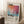May include: Framed art print featuring abstract colorful brushstrokes in pink, orange, blue and purple tones with "Mark Rothko" text and exhibition dates. Light wood frame leaning against white wall near window with natural lighting. White coffee cup on saucer sits on wooden surface beside woven throw blanket on fluffy white rug.
