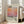 May include: Framed art print leaning against white wall beside beige couch in bright living room with large windows. The poster features abstract orange and pink gradient colors with "Mark Rothko" text and descriptive paragraph below. Light wood frame, approximately 2-3 feet tall, positioned on light wooden floor with natural sunlight streaming across the space.