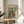 May include: Abstract art print with colorful geometric squares in teal, orange, yellow and dark green tones displayed in thin wooden frame on round wooden side table next to beige upholstered chair, with plant shadows and natural lighting in minimalist room setting