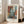 May include: Framed abstract art poster with geometric blocks in muted blues, oranges, and earth tones, leaning against white wall next to beige sofa in bright living room with large windows and wooden floors