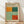 May include: Framed exhibition poster for Mark Rothko leaning against white wall on wooden floor. Features abstract color blocks in orange, dark green, light green, and red-orange arranged in rectangular sections. Cream background with black text showing gallery information and exhibition dates. Natural wood frame with soft lighting casting shadows on wall.