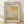 May include: Framed exhibition poster for Mark Rothko displayed on light wooden floor against white wall with soft natural lighting. Poster features abstract geometric composition in muted yellows, beiges and grays with exhibition text at top including gallery name and dates. Natural wood frame surrounds cream-colored print with minimalist modern aesthetic.