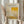 May include: Person holding framed exhibition poster featuring Mark Rothko artwork with yellow, beige and muted green abstract color blocks. Light wood frame against neutral curtained background. Dried pampas grass stems visible on left side. Soft natural lighting creates warm, minimalist aesthetic.