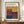May include: Framed exhibition poster featuring Mark Rothko's abstract color field artwork with warm yellows, deep reds, purples, and navy blue rectangular blocks. Displayed on wooden console table beside white ceramic vase and stacked books against cream paneled wall. Brown wooden frame complements vintage-style poster design with exhibition details and dates.