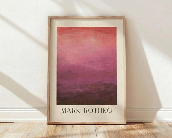 May include: Framed art print with gradient color field transitioning from coral pink at top through magenta to deep burgundy at bottom, displayed in light wood frame with cream matting against white textured wall on light wooden floor with natural window shadows