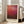 May include: Framed poster print with deep red and burgundy abstract color field painting in light wood frame, displayed against white wall next to beige upholstered sofa with throw pillows in bright living room with large windows and natural lighting.