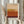 May include: Person holding framed abstract art print featuring horizontal bands of warm colors transitioning from cream at top through yellow, orange, to deep burgundy at bottom, displayed against white curtained window with dried pampas grass, in light wooden frame on white mat