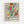 Framed poster with vibrant Matisse-inspired abstract floral design featuring bold organic shapes in red, yellow, green, blue, and orange on cream background. Light wood frame against white wall. Text at bottom reads "Celebrating Colors of Life" with descriptive paragraph about adding color to spaces with bold shapes and vivid hues.