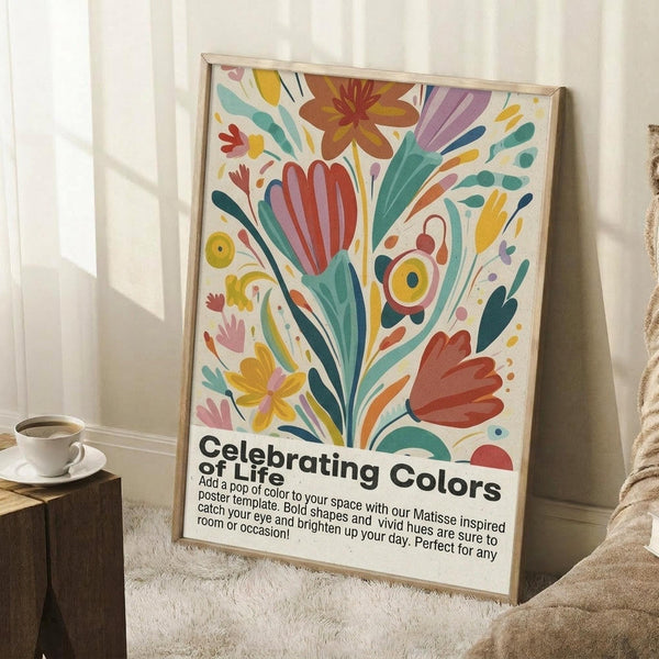 May include: A framed poster with colorful abstract floral design in Matisse-inspired style, featuring bold shapes in red, yellow, green, orange, and purple on cream background. The artwork shows stylized flowers, leaves, and organic forms with "Celebrating Colors of Life" text at bottom. Displayed in light wood frame leaning against white wall on textured rug, with coffee cup on wooden stool nearby in bright, airy room setting.