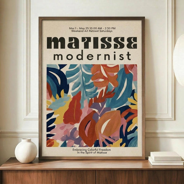 May include: Framed modernist art poster with abstract colorful leaf and floral shapes in blues, oranges, yellows, and pinks displayed on wooden sideboard beside white ceramic vase and stacked books against cream paneled wall
