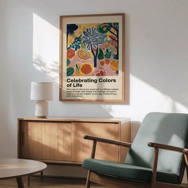 May include: Colorful Matisse-inspired poster with abstract fruits, leaves and botanical shapes in blues, oranges, greens and pinks, titled "Celebrating Colors of Life" in wooden frame above light wood sideboard. Modern sage green armchair with wooden arms sits nearby with small round table. Bright natural sunlight creates geometric shadows on white wall in contemporary living room setting.