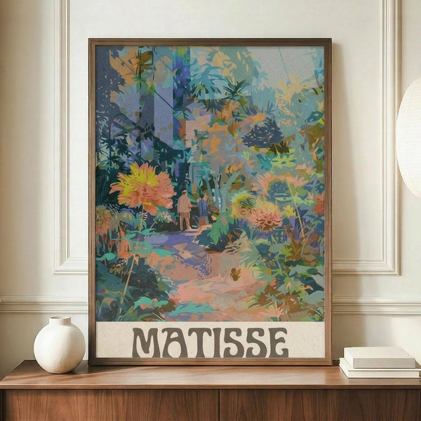 May include: Framed art print in warm wood frame displayed on wooden sideboard alongside white ceramic vase and stacked books. The colorful botanical artwork features vibrant tropical foliage, palm trees, flowers in coral and yellow tones, and a small figure on a winding path through lush vegetation. The piece has layered, painterly textures with blues, greens, oranges and purples creating a dreamy garden scene against cream gallery wall with white molding.