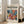 May include: Framed poster with "matisse modernist" text and abstract botanical artwork in vibrant blues, oranges, pinks and yellows, leaning against white wall beside beige sofa in bright living room with hardwood floors and large windows