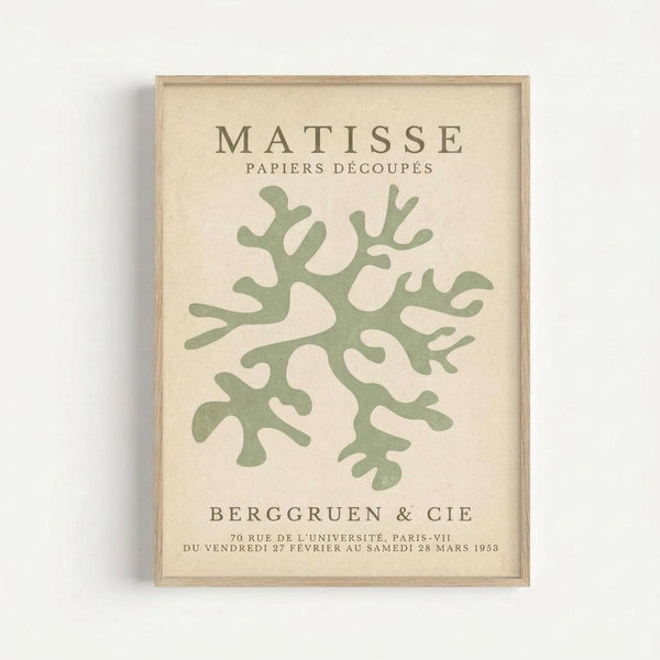 May include: Framed art print displayed on white wall featuring green organic coral-like shape on cream background, with text reading "Matisse Papiers Découpés" at top and "Berggruen & Cie" gallery information at bottom in brown lettering, shown in light wood frame