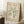 May include: Framed vintage-style art print featuring green organic coral-like shape on cream background, displayed in light wood frame leaning against white wall. Coffee cup on wooden side table and textured white rug visible. Natural lighting creates soft shadows in minimalist room setting.