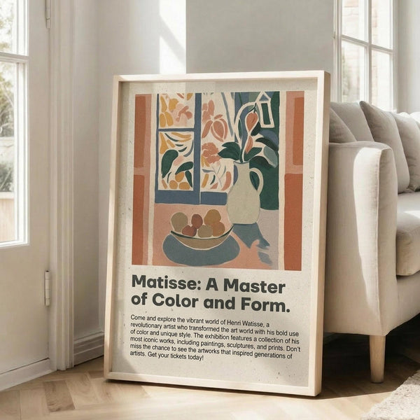 May include: Framed art poster displaying a colorful still life scene with geometric shapes, flowers in a vase, fruit bowl, and window view in muted oranges, blues, and greens. Light wooden frame leans against white wall beside beige sofa in bright living room with large windows and natural lighting.