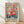 May include: A framed floral art print leaning against a white wall on light wooden flooring. The artwork features vibrant watercolor-style flowers in coral, pink, orange, and yellow with blue and green foliage against a cream background. The word "MATISSE" appears in bold black letters at the bottom. Natural light casts soft shadows across the scene, and the print is displayed in a simple light wood frame.