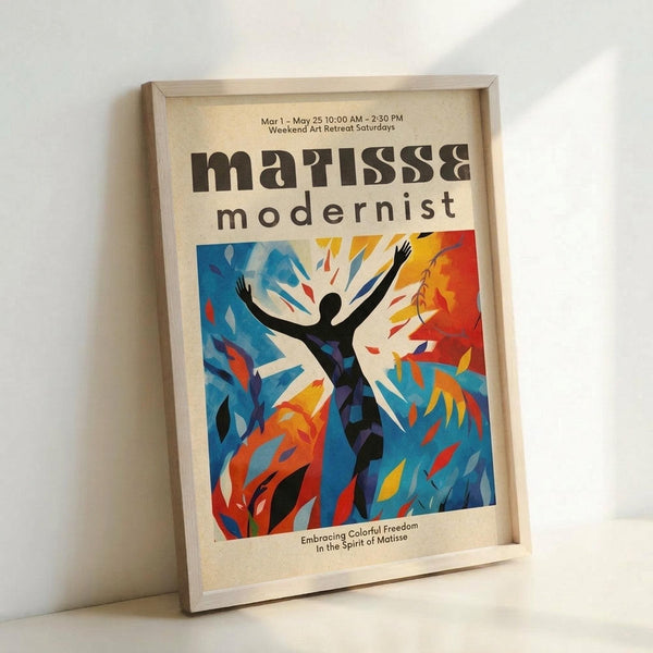 May include: Framed poster displaying modernist artwork with vibrant blue, orange, and red abstract shapes surrounding a black silhouette figure with raised arms. Text reads "matisse modernist" at top and "Embracing Colorful Freedom In the Spirit of Matisse" at bottom. Light wood frame sits against white wall on white surface.