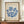 May include: Framed vintage exhibition poster featuring blue coral-like seaweed forms on cream textured background, displayed on wooden sideboard with small white ceramic vase and stacked books in elegant room with white paneled walls.