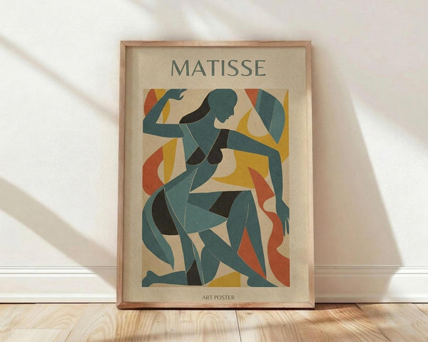 May include: Framed art poster featuring abstract cut-out style figure in teal and dark green against cream background with yellow and orange geometric shapes. The minimalist artwork shows a stylized human form created from curved, flowing shapes. Displayed in light wood frame leaning against white wall on wooden floor with soft natural lighting casting shadows.