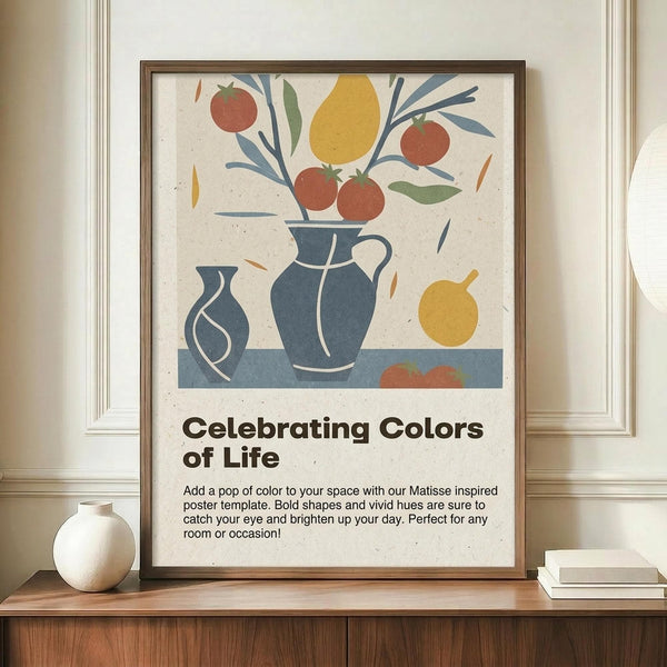May include: Framed poster with Matisse-inspired still life artwork featuring blue ceramic vases, colorful fruit including red apples and yellow pear, green foliage on cream textured background. Text reads "Celebrating Colors of Life" with description below. Brown wooden frame displayed on wood sideboard next to white ceramic vase and stacked books in neutral-toned room with white paneled walls.