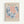 Framed vintage exhibition poster featuring abstract cut-paper designs in coral pink and blue tones on cream background. The artwork displays flowing, organic shapes resembling seaweed or flames. Text indicates a 1958 Paris gallery show. Natural wood frame against white wall in minimalist interior setting.